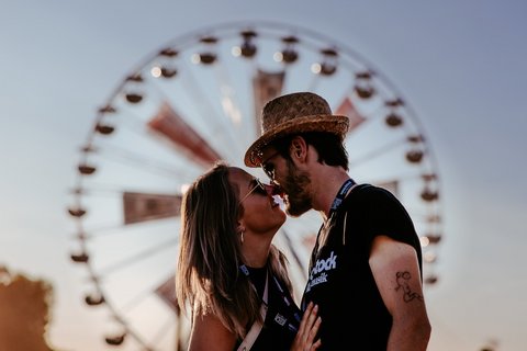 Ein Pärchen küsst sich vor dem Riesenrad am Woodstock.