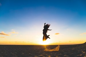 Silhouette einer Frau, die vor Sonneuntergang springt