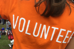 Eine Person mit einem orangen T-Shirt auf dem Volunteer steht, ist im Vordergrund