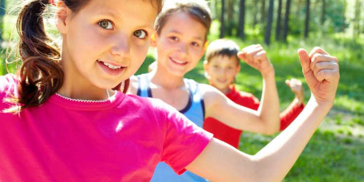 Drei Kinder stehen hintereinander, zeigen mit ihren linken Armen (Muskel)Kraft und Stärke.  