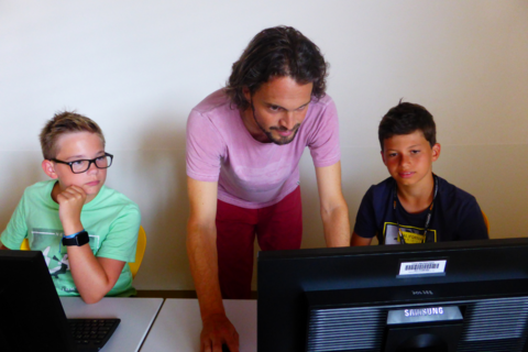 Kinder mit Lehrer vor Laptops, DigiCamp 2021