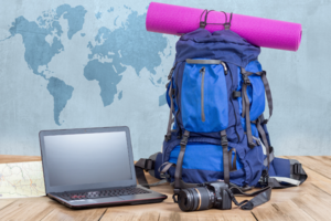 Laptop, Reisegepäck, Weltkarte im Hintergrund