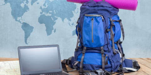 Laptop, Reisegepäck, Weltkarte im Hintergrund