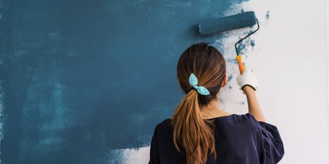 Frau, die eine Wand blau malt