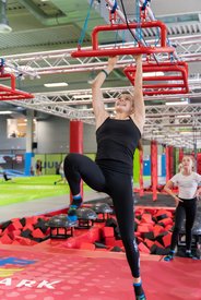 Eine junge Frau in Sportausrüstung bewältigt die Hindernisse des 4youCard Ninjas im Jump Dome Linz