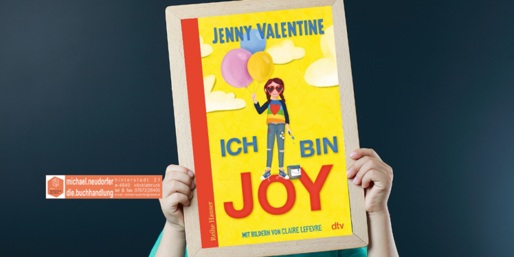 Kind hält eine Tafel hoch mit dem Cover des Buches: Ich bin Joy