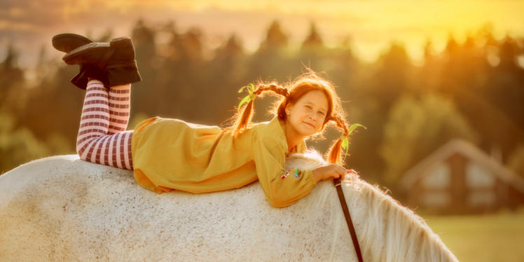 Mädchen - als Pippi Langstrumpf verkleidet - liegt auf dem Rücken eines Pferdes