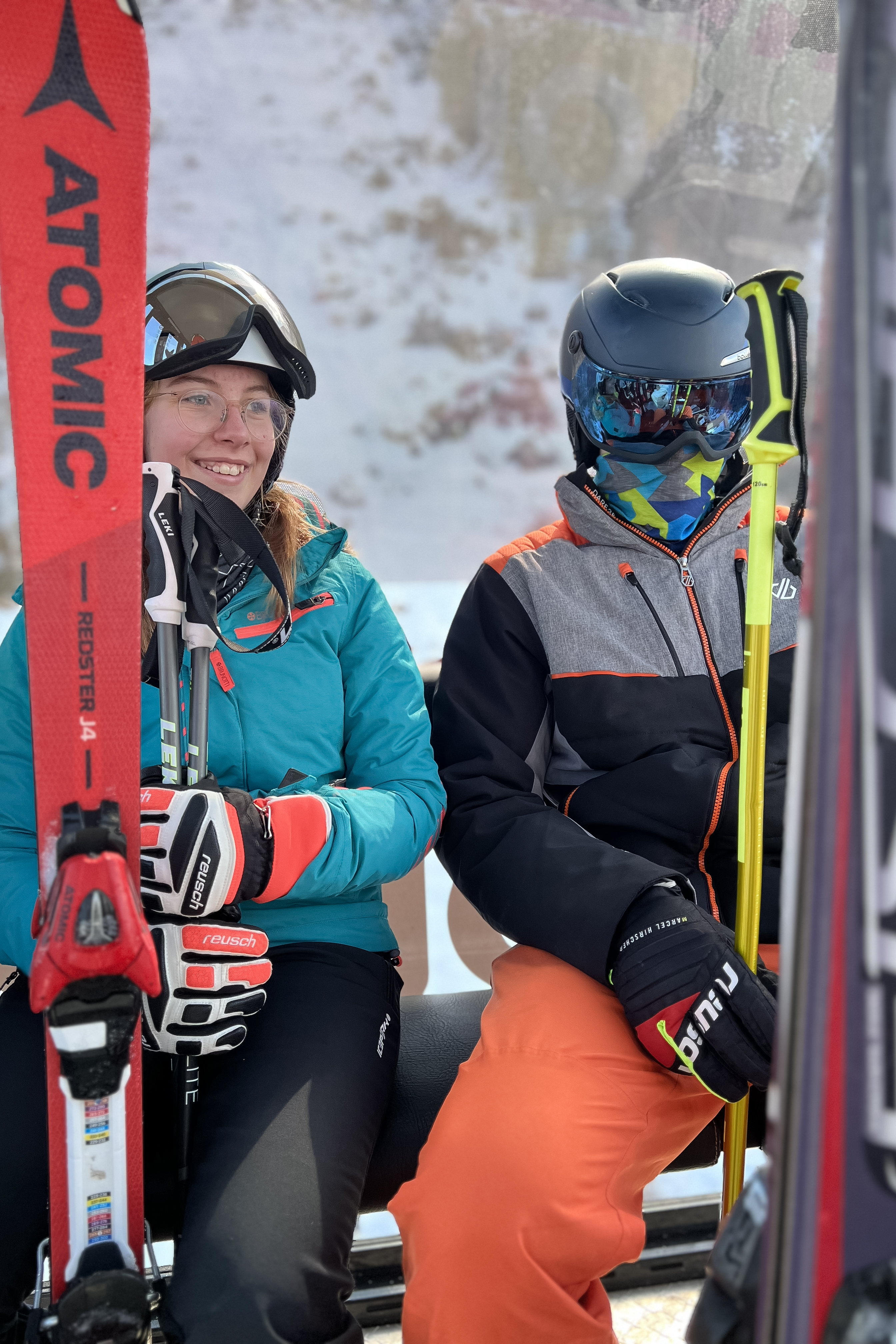 Zwei Jugendliche in Skiausrüstung in einer Gondel