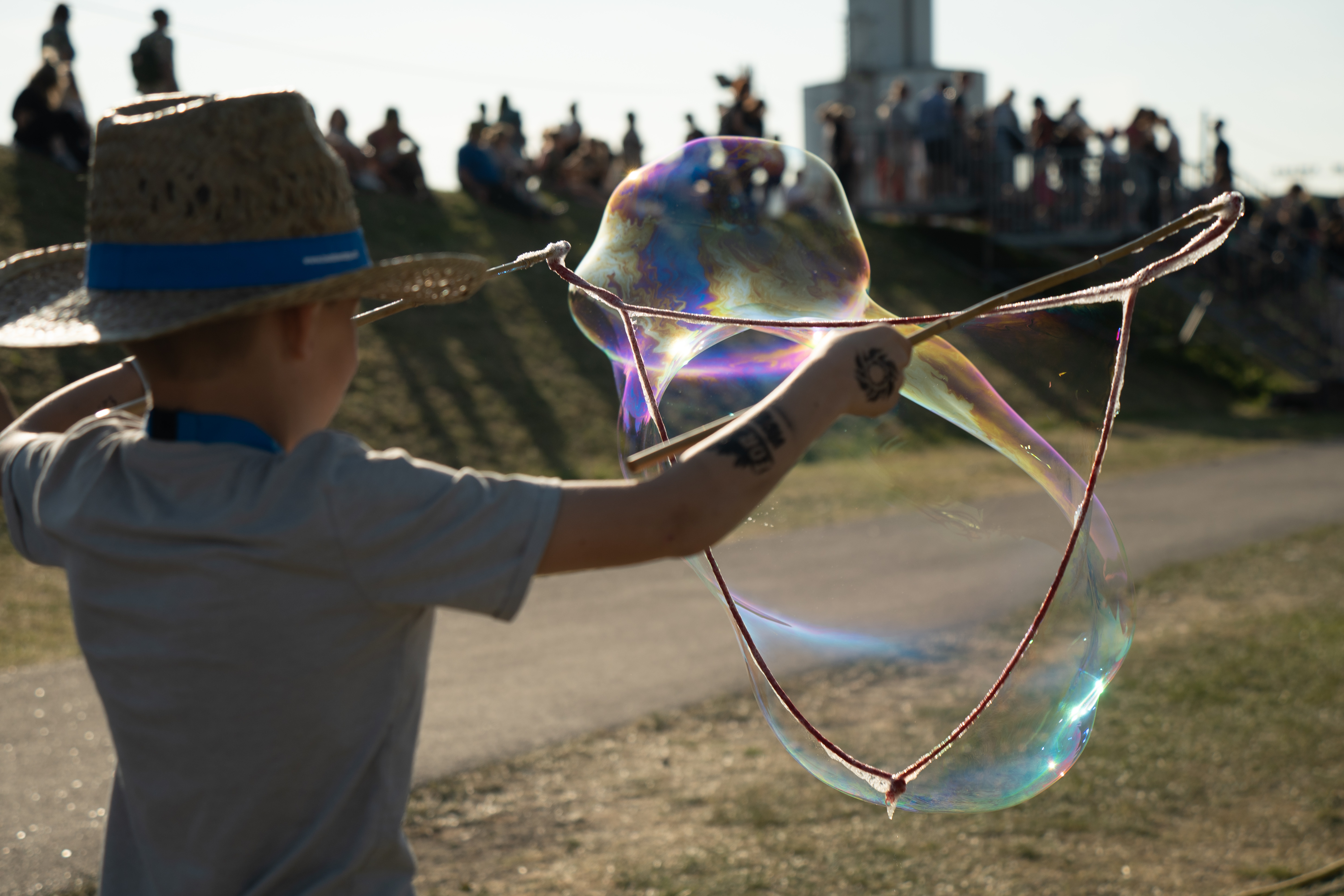 Ein Kind mit Hut  macht Riesenseifenblasen