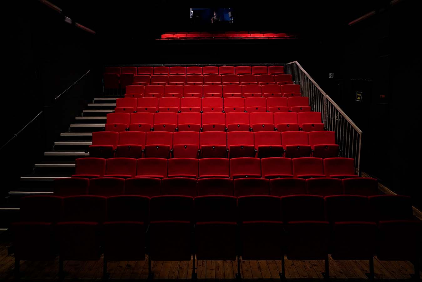 ein langer dunkler Saal mit roten Stühlen